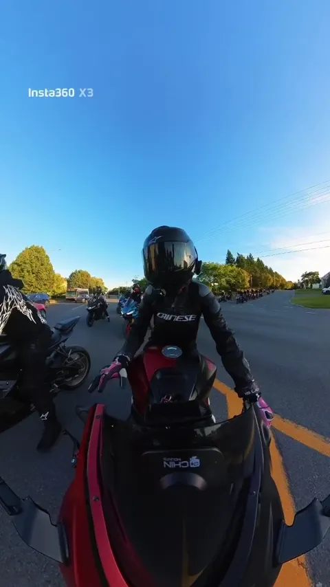 Rider on a red Ninja with the motorcycle convoy behind